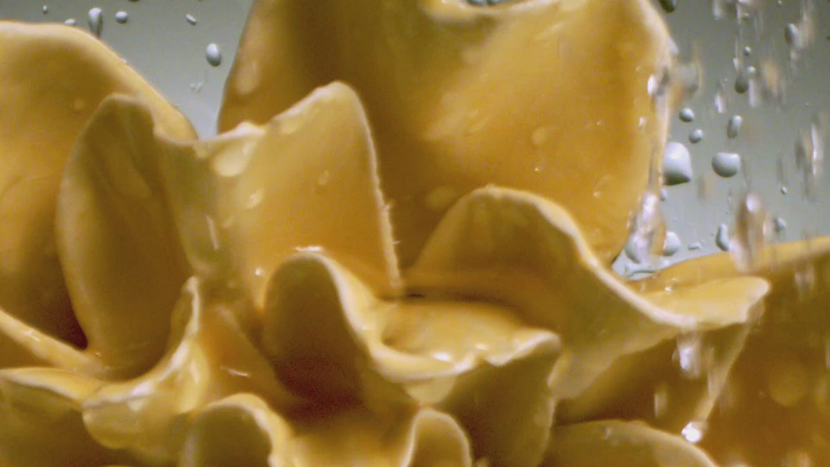 Water pours over a warm yellow ceramic flower in macro — the orange wall art collection in warm glazes.